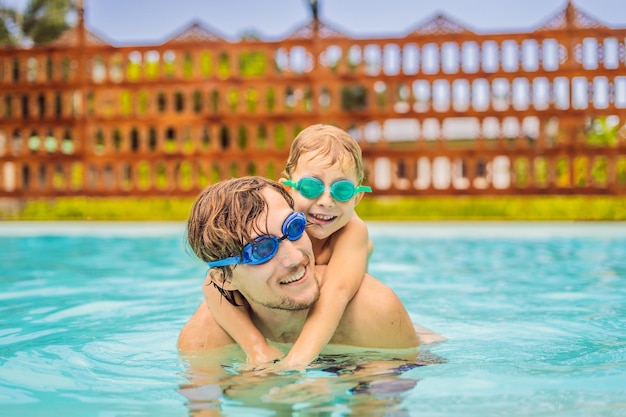 Papà e figlio in occhialini da nuoto si divertono in piscina