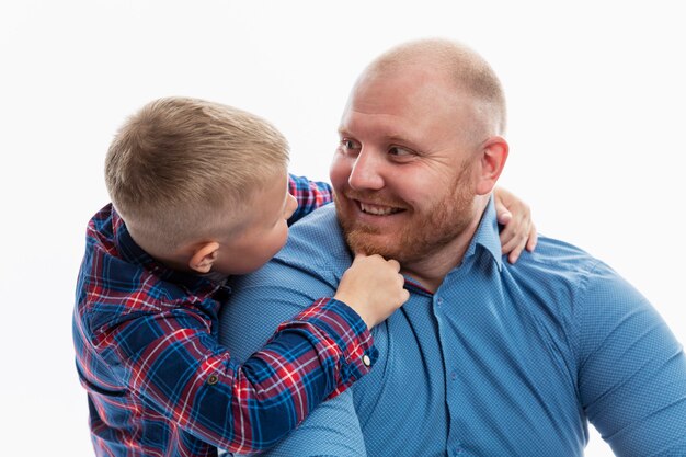 Papà e figlio piccolo sorridono e si abbracciano. Amore e tenerezza in una relazione. Isolato