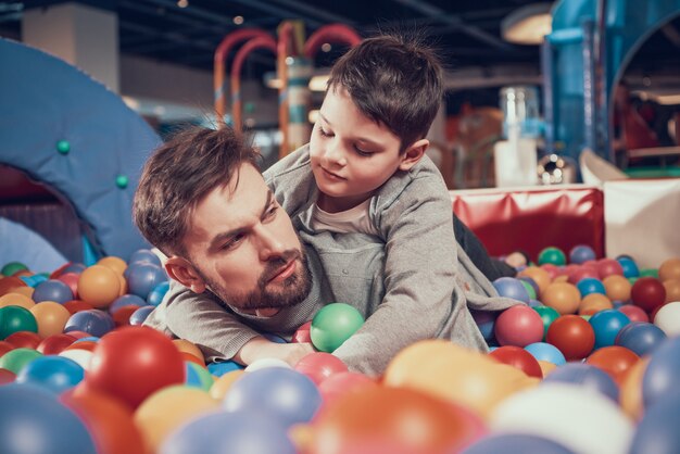 Papà e figlio seri in stagno con le palle in parco di divertimenti.