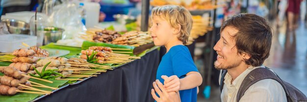 Papà e figlio sono turisti sul formato lungo dell'insegna del mercato alimentare asiatico della via pedonale