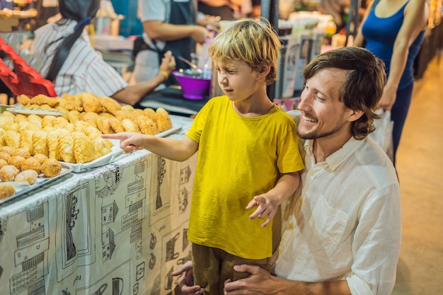Papà e figlio sono turisti sul mercato alimentare asiatico di Walking Street