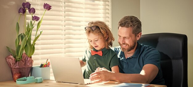 Papà e figlio sorridenti con gli occhiali usano il laptop a casa blog di famiglia ragazzo nerd fare i compiti