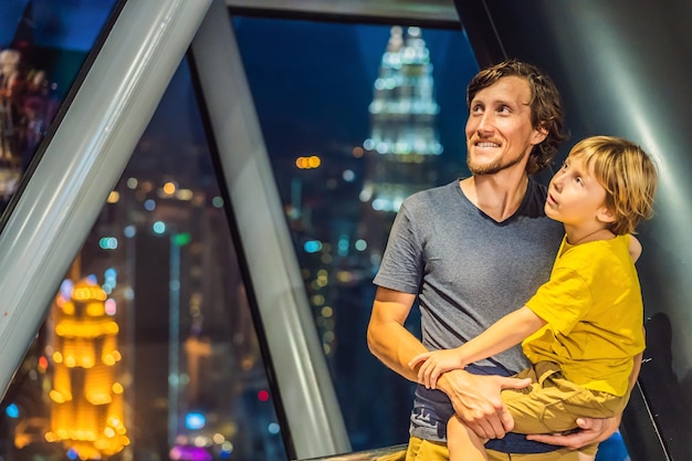 Papà e figlio stanno guardando il paesaggio urbano di Kuala Lumpur Vista panoramica dello skyline della città di Kuala Lumpur sera al tramonto grattacieli in Malesia Viaggiare con il concetto di bambini