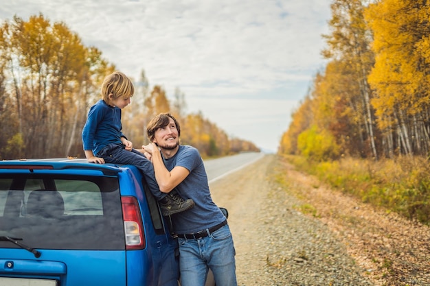 Papà e figlio stanno riposando sul lato della strada durante un viaggio su strada con il concetto di bambini