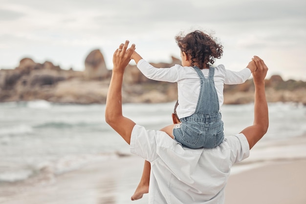 Papà e figlio sull'acqua sulla spiaggia in vacanza in famiglia insieme per una divertente pausa estiva per legare nella natura Felice padre e figlio si godono le vacanze sull'oceano con la giovane ragazza che tiene il genitore in equilibrio sulle spalle