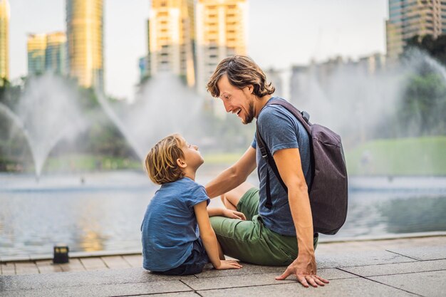 Papà e figlio turisti sullo sfondo della fontana sul lago di notte vicino alle Torri Gemelle con la città sullo sfondo Kuala Lumpur in Malesia