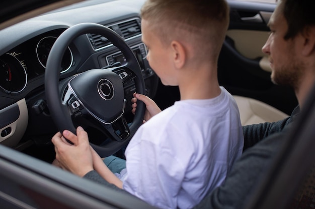 Papà e un ragazzo carino tengono il volante di un'auto con le mani