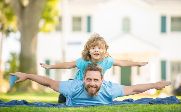 Papà felice che si diverte con il bambino si rilassa insieme sulla relazione con l'erba del parco verde