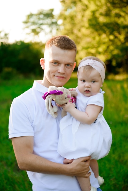 Papà felice con la figlia che gioca sull'erba nel parco la sera.