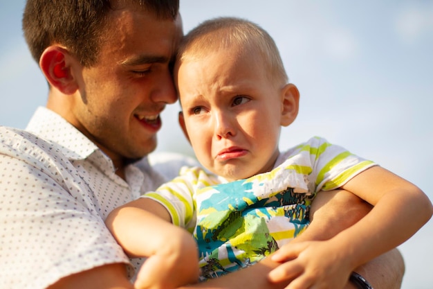 Papà felice conforta il suo figlioletto che piangePaternità