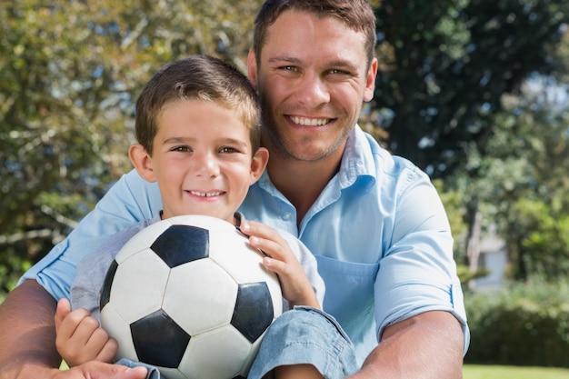 Papà felice e figlio con un calcio in un parco