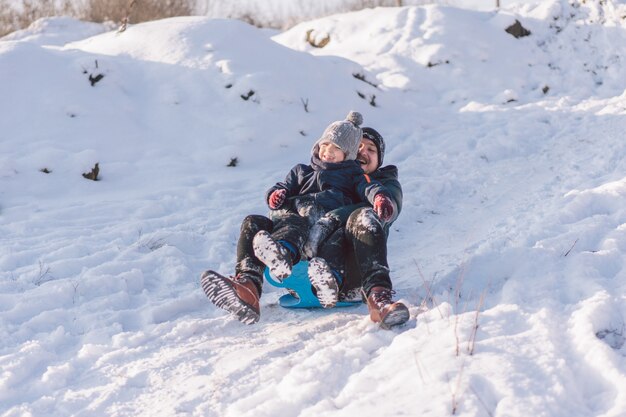 Papà felice e ragazzino che giocano con la slitta da neve