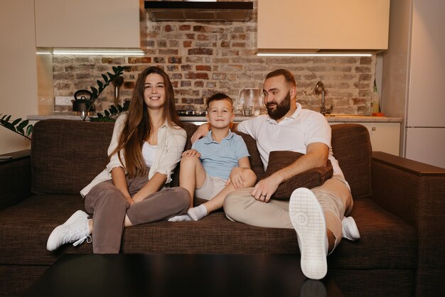 Papà, figlio e mamma stanno guardando con interesse la TV sul divano dell'appartamento