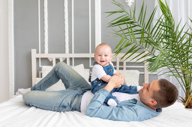 Papà gioca sul letto con la paternità felice del figlio del bambino