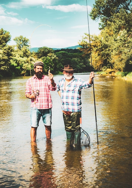 Papà in pensione e figlio barbuto maturo pescatori barbuti felici in acqua uomini che si rilassano sullo sfondo della natura bru