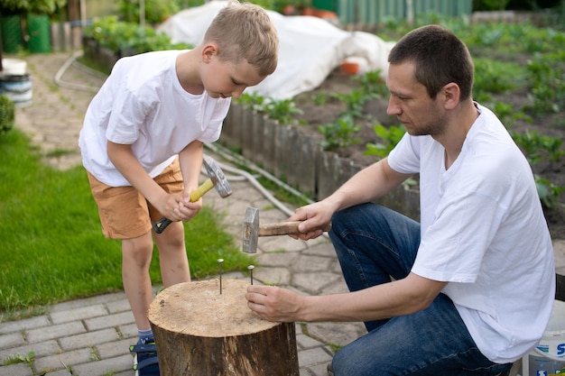 Papà insegna a suo figlio a piantare chiodi su un albero