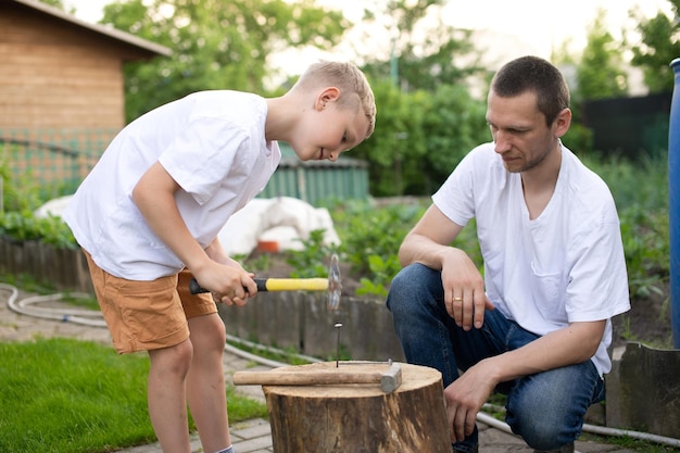 Papà insegna a suo figlio a piantare chiodi su un albero