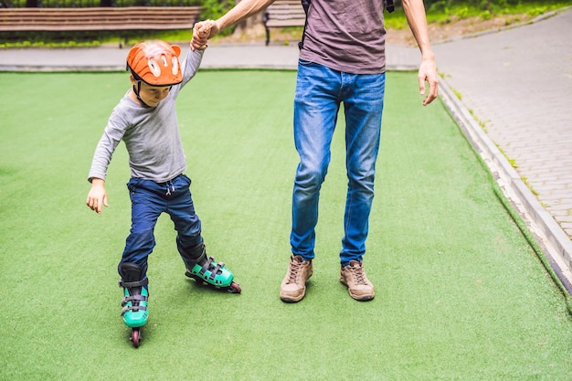 Papà insegna al figlio a pattinare nel parco.