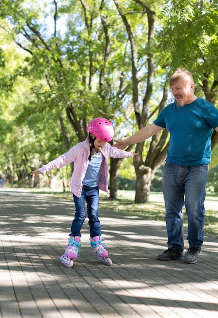 Papà insegna alla figlia a pattinare nel parco