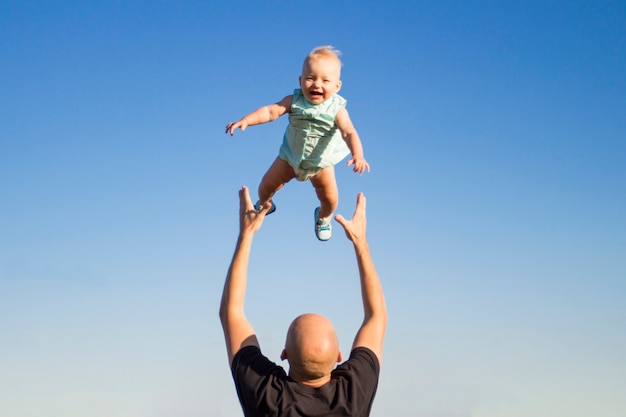 Papà lancia suo figlio contro il cielo blu.