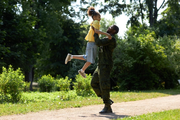 Papà militare afroamericano che gioca con suo figlio durante la loro passeggiata all'aperto