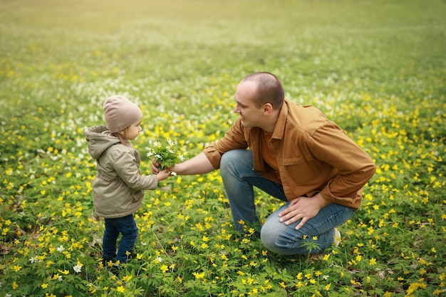 Papà regala alla figlia piccola un mazzo di fiori gialli.