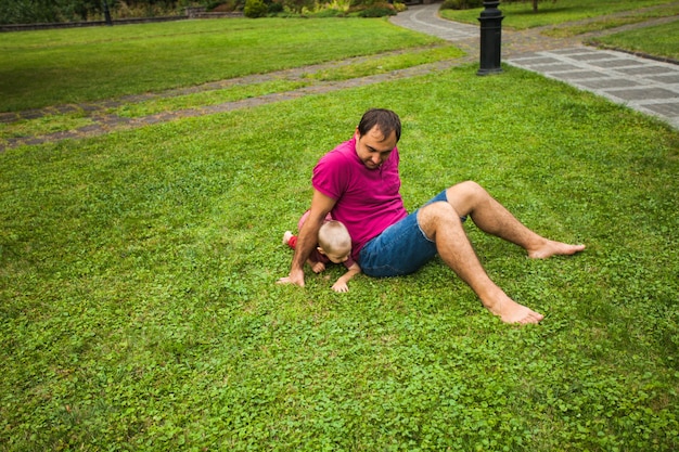 Papà si è seduto sull'erba e giocava con suo figlio nel parco