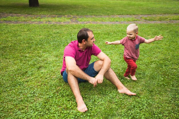 Papà si è seduto sull'erba e giocava con suo figlio nel parco