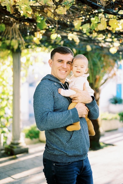 Papà sorridente con un bambino in braccio si trova nel cortile
