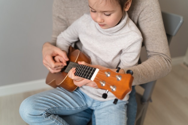 Papà suona la chitarra con sua figlia. Il bambino impara a suonare uno strumento musicale con un tutor. Duetto musicale di un padre con un bambino.