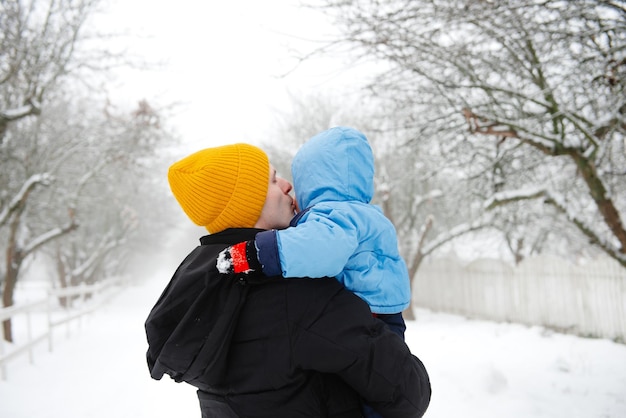 Papà tiene in braccio suo figlio in inverno Papà e suo figlio Papà e il suo bambino Divertimento invernale L'infanzia felice di un bambino