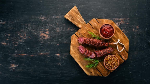 Paperoni di salsiccia Salame con paprika Su fondo di legno nero Vista dall'alto Spazio libero per il testo