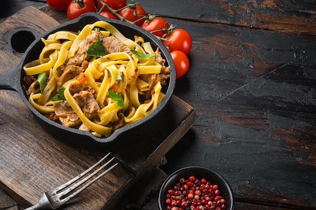 Pappardelle fatte in casa allo stufato di coniglio, in padella o pentola in ghisa, sul vecchio tavolo in legno scuro