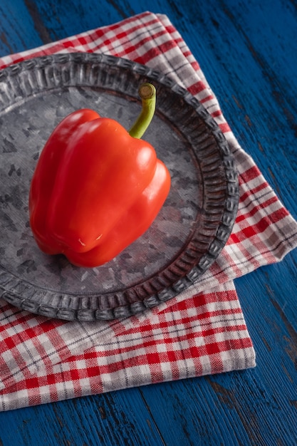 Paprika rossa fresca in stile rustico su uno sfondo di legno blu