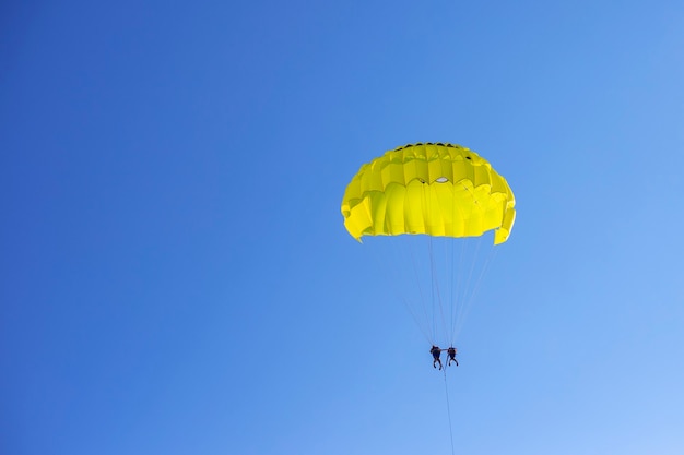 Paracadute giallo con persone nel cielo blu