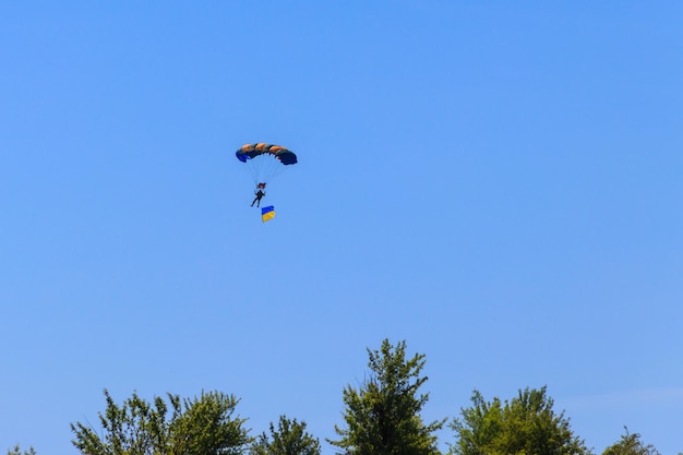 Paracadutista che porta la bandiera dell'Ucraina nel cielo blu chiaro