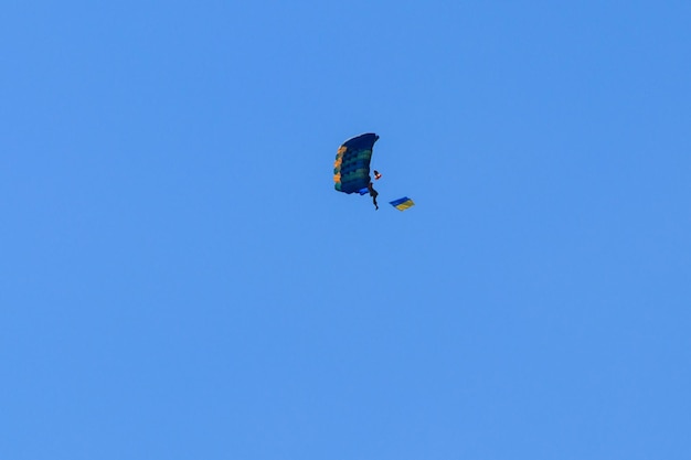 Paracadutista che porta la bandiera dell'Ucraina nel cielo blu chiaro