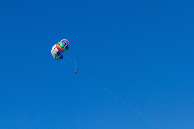 Paracadutista che vola con un paracadute colorato in motoscafo sul mare