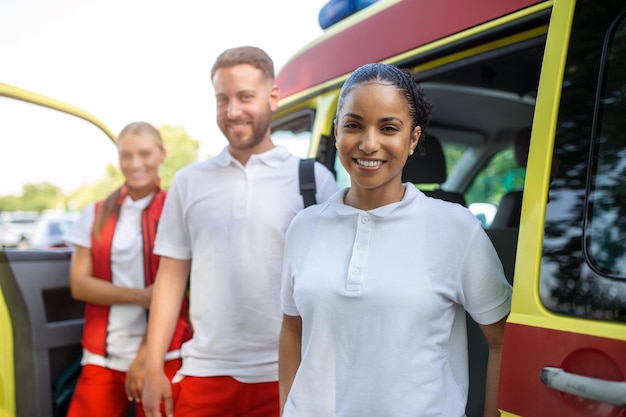 Paramedici multietnici in piedi davanti a un'ambulanza Medici di emergenza e infermieri in piedi davanti all'ambulanza