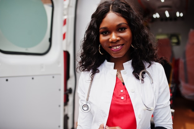 Paramedico femminile afroamericano in piedi davanti all'auto ambulanza