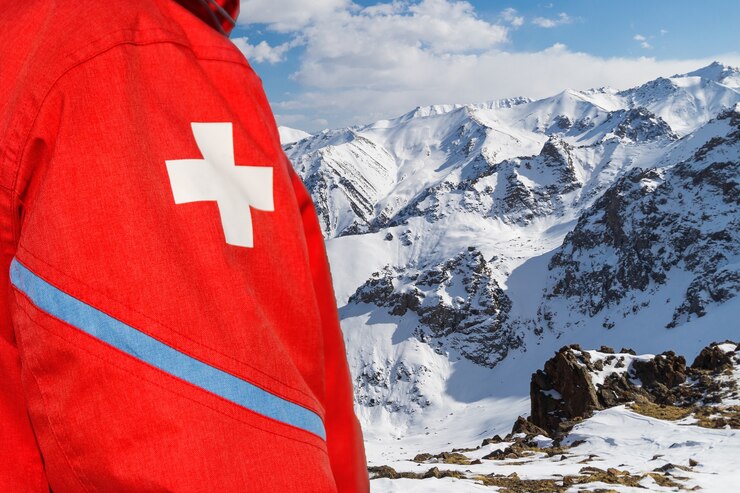 Paramedico sul pendio della montagna in abiti rossi con croce bianca