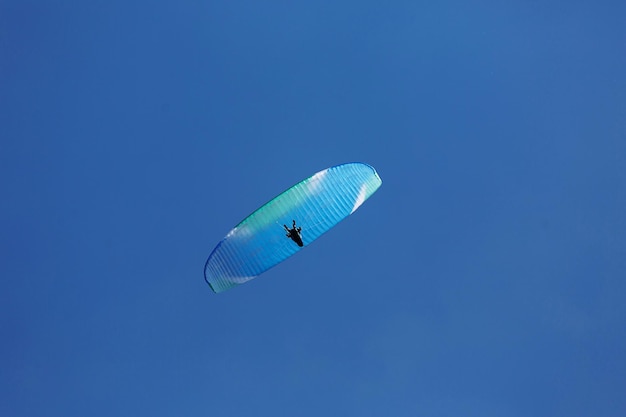 Parapendio blu che vola nel cielo con le nuvole in una giornata di sole