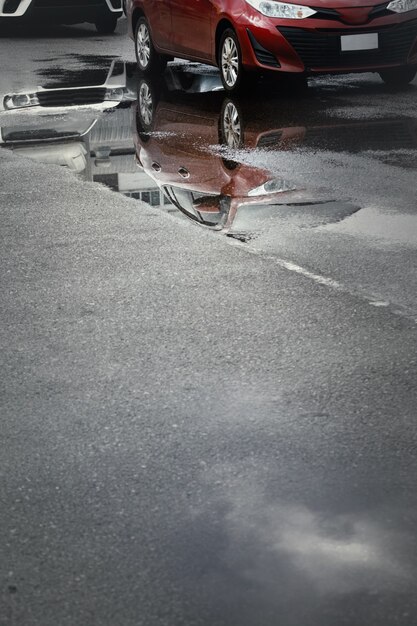 Parcheggi bagnati dopo la caduta della pioggia battente con riflesso nella pozzanghera sul terreno. Messa a fuoco selettiva.