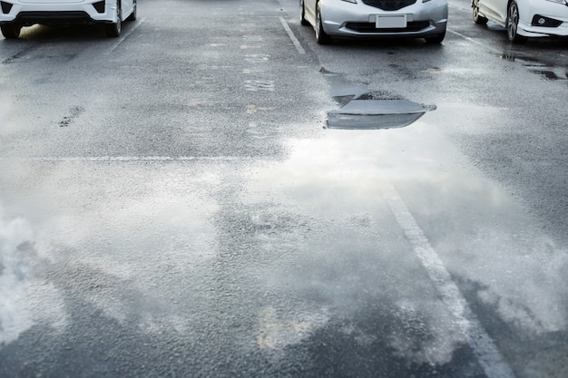 Parcheggi bagnati dopo la pioggia caduta con riflesso del cielo nella pozzanghera sul terreno. Messa a fuoco selettiva.