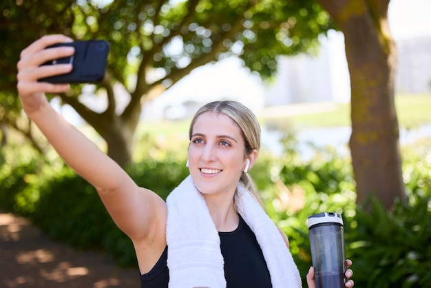 Parcheggia donna felice o influencer del fitness che si fa un selfie durante l'allenamento in esecuzione o allenamento in un parco Corridore del sorriso o atleta ragazza in buona salute in cuffia che parla di immagini o foto per rilassarsi durante una pausa