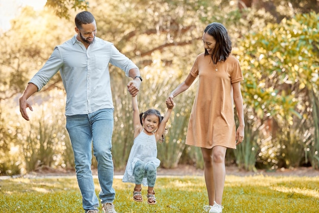 Parcheggia la famiglia e tieniti per mano con il bambino volante per un legame divertente e una passeggiata di benessere insieme Madre e papà felici con una giovane figlia in Canada che giocano nella natura per il tempo libero al sole estivo