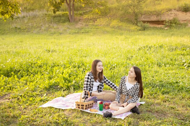 Parcheggiare vicino alla casa. Due ragazze carine sull'erba al sole che sorridono, ridono