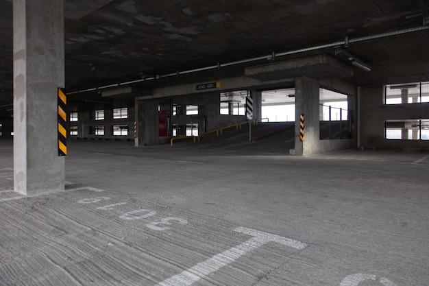 Parcheggio a più livelli con segnaletica luminosa durante il giorno con parcheggi vuoti, con colonne e piastrelle della pavimentazione