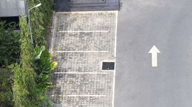 Parcheggio esterno in cemento e linea bianca e freccia bianca e albero.