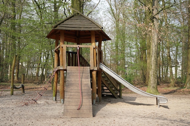 Parco giochi nel bosco con capanna in legno e scivolo